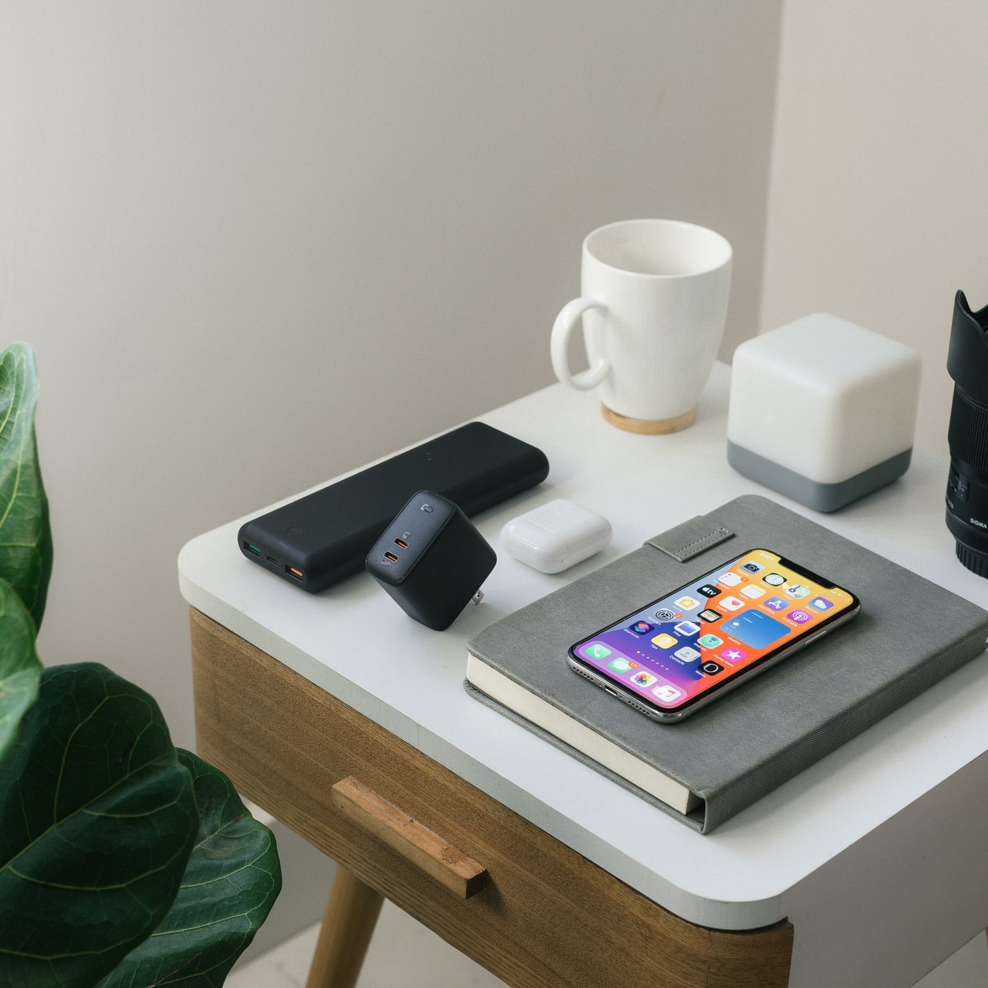 Smartphone on a notebook beside charging accessories and a mug