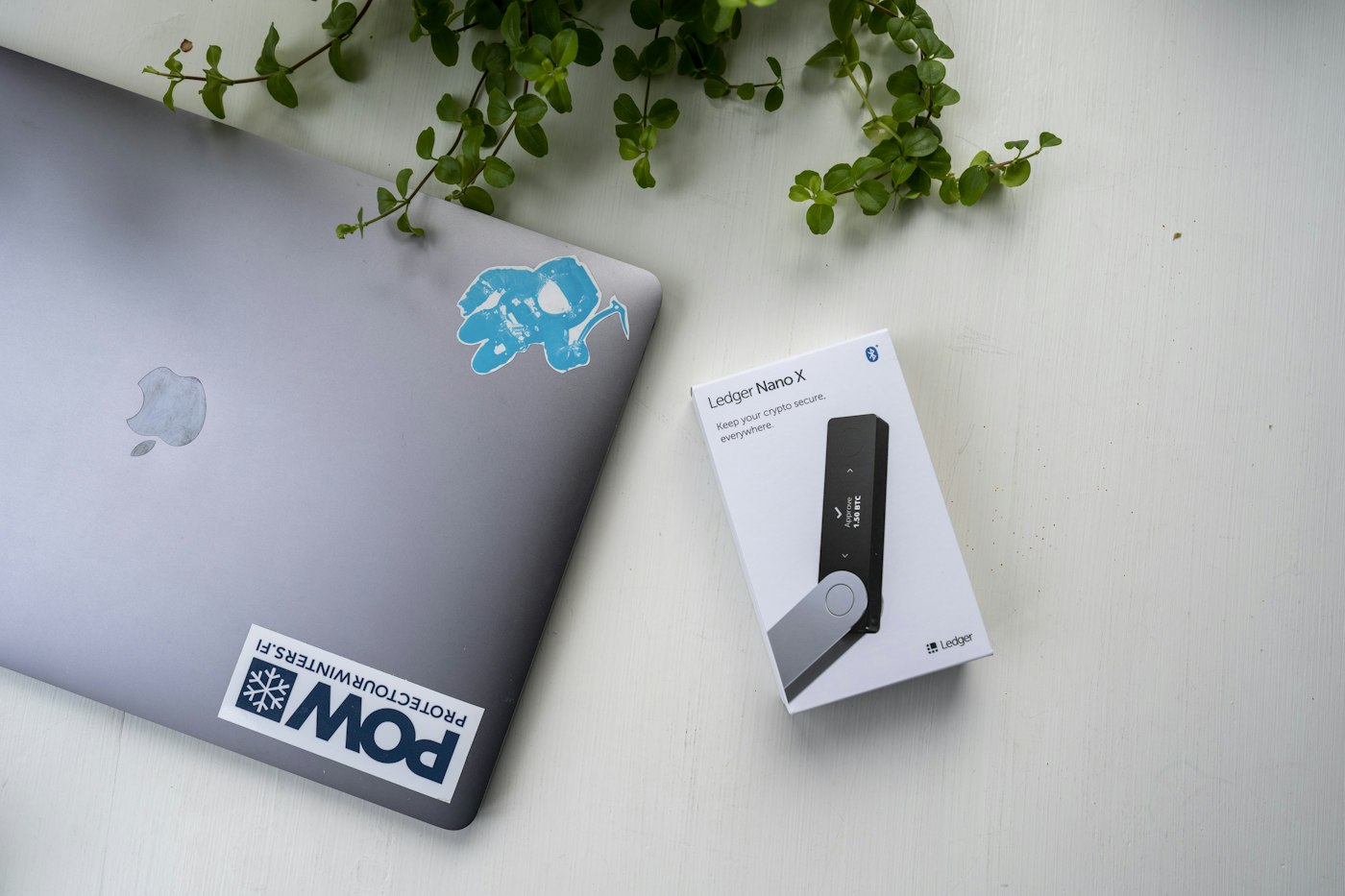 Laptop beside Ledger Nano X packaging on a white desk